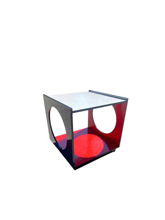 A modern geometric side table or end table with a square top, open cube frame, and circular cutouts, featuring a white top surface, dark gray frame, and red interior panels.
